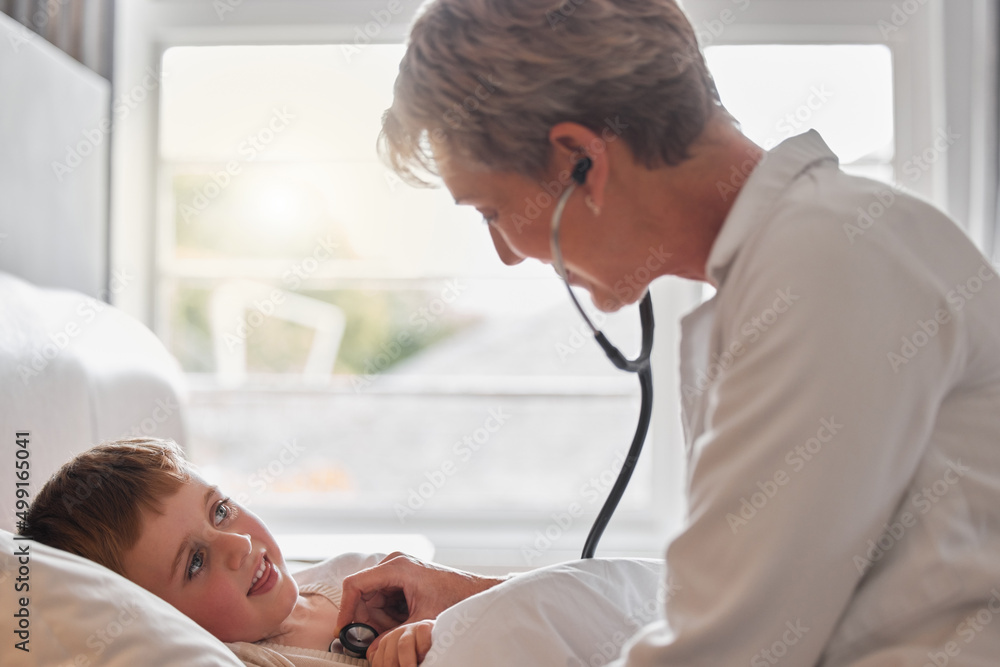 Obraz premium Hows this big boy feeling today. Shot of a doctor examine a little boy with a stethoscope in bed at home.