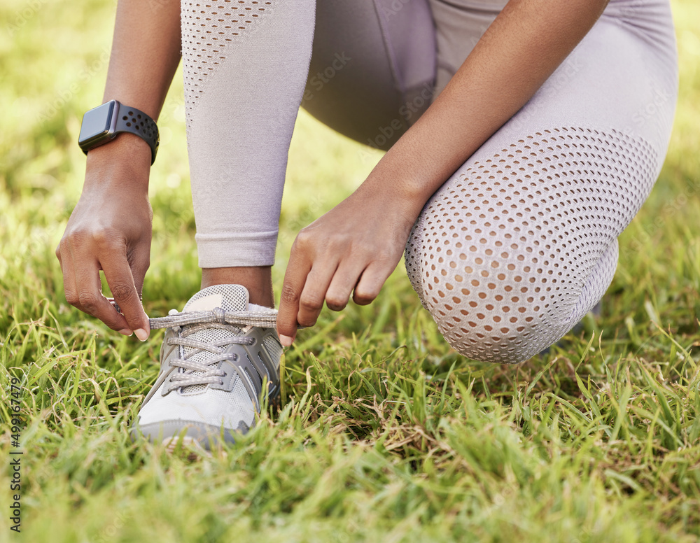 Its about at least having the determination to start. Closeup shot of an unrecognisable woman tying her shoelaces while exercising outdoors.