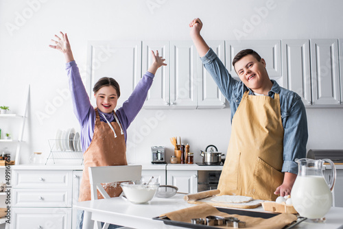Excited friends with down syndrome standing near food in kitchen.