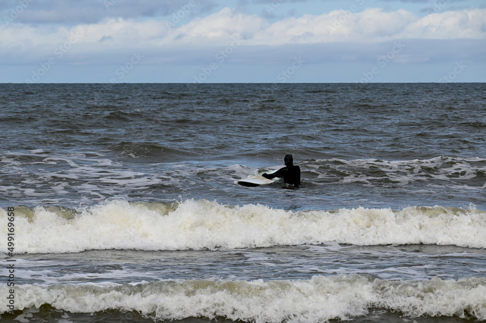 Lone surfer at the beach in cold water with wetsuit on, Baltic Sea