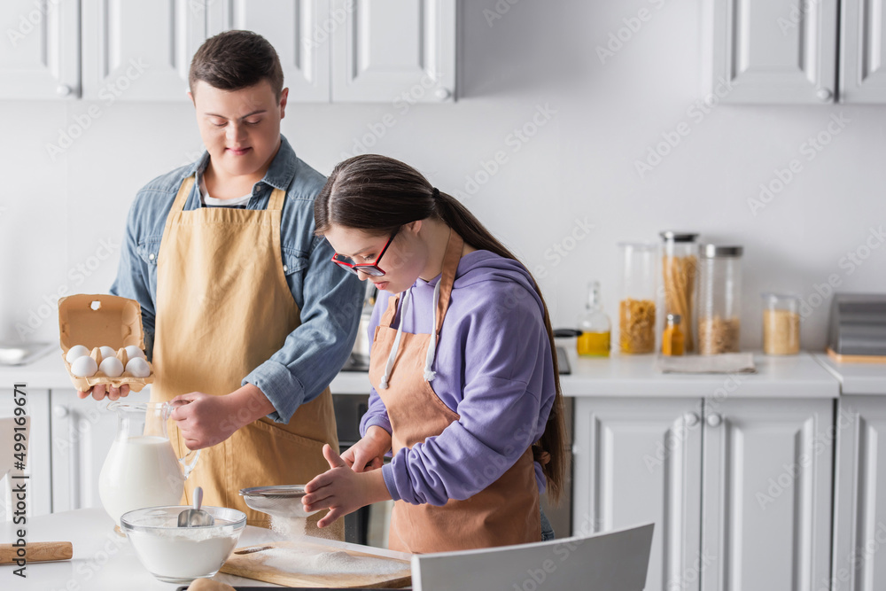 Couple with down syndrome cooking together in kitchen. Couple with down syndrome cooking together in kitchen.