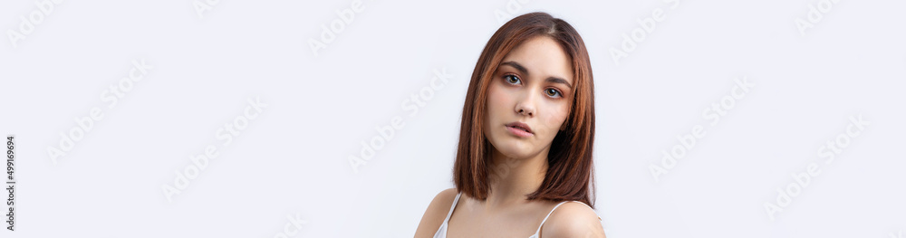 Naklejka premium Beautiful smiling woman with clean skin, natural make-up and white teeth on a gray background