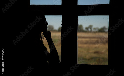 silhouette of a girl looking out of the window, with a pensive, sad, lonely attitude