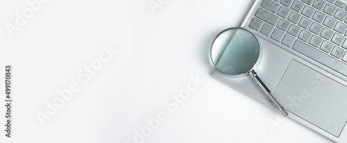 Banner with magnifying glass on laptop. Information search concept. Digital information analysis. Online databases study. Copy space. High quality photo