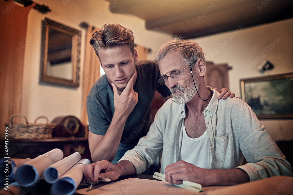 Putting their thinking caps on. Shot of a father and his son working on a design for their family business at home. Putting their thinking caps on. Shot of a father and his son working on a design for their family business at home.