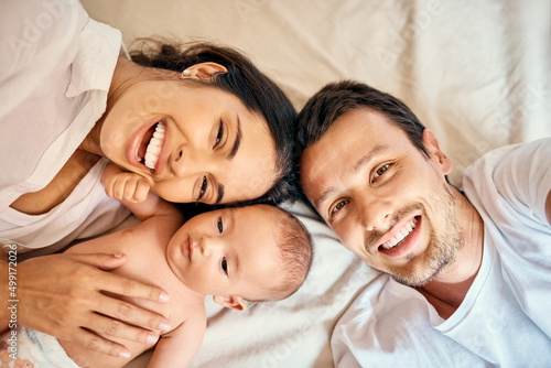 50 mommy, 50 daddy = 100 cute. High angle shot of a happy mother and father taking selfies with their baby boy at home.