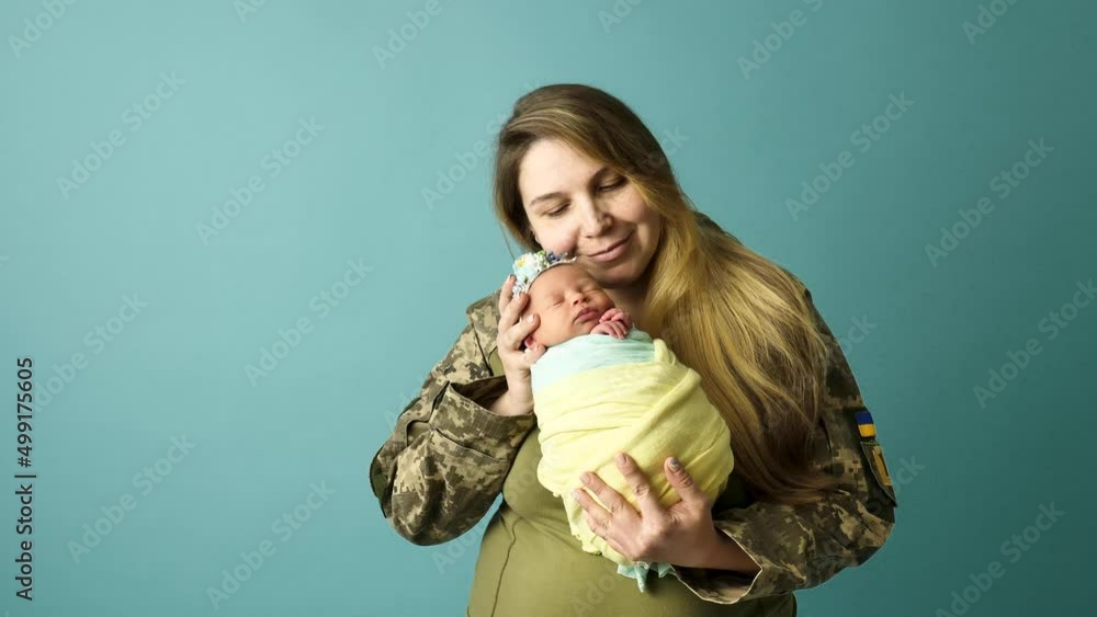 A Ukrainian mother in military uniform with a little child in the colors of a yellow blue flag during the 2022 war. Close-up in the studio, insulated background. The most important heroes of women. A Ukrainian mother in military uniform with a little child in the colors of a yellow blue flag during the 2022 war. Close-up in the studio, insulated background. The most important heroes of women.
