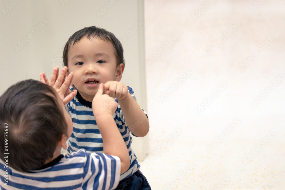 Portrait of happy asian boy smile while pointing his finger into his reflection in the mirror. Portrait of happy asian boy smile while pointing his finger into his reflection in the mirror.
