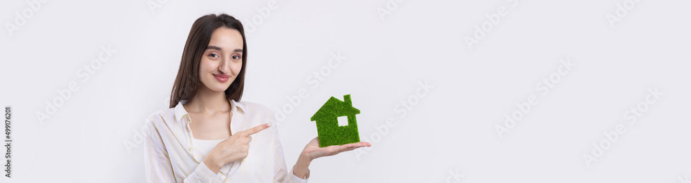 A young girl realtor holds a model of a green house in her hands. Sale of ecological real estate. A young girl realtor holds a model of a green house in her hands. Sale of ecological real estate.
