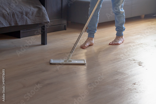 A teenage boy is mopping the floor in a room with a mop, a child is cleaning the house