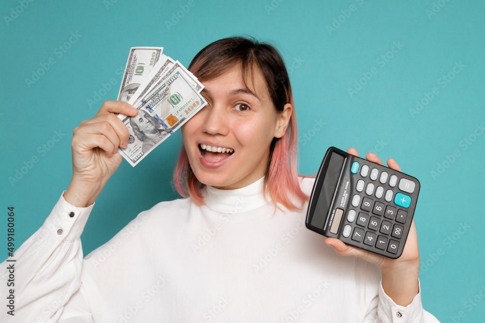 Young woman holding calculator and money isolated on blue background, business account and finance concept Young woman holding calculator and money isolated on blue background, business account and finance concept