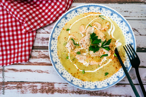 Exquisite dish with a homemade cream of poultry soup with chicken pieces, parsley and cream on a rustic or country style wooden table. Natural and simple food concept. Copy Space. photo