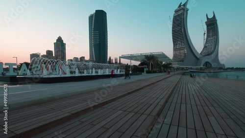 Lusail Corniche at the marina in Lusail, Qatar  sunset shot showing fountain, people walking on the promenade with skyline in background