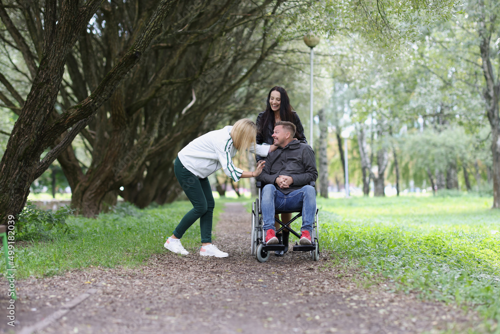 Happy young disabled man communicates with girlfriends in park Happy young disabled man communicates with girlfriends in park