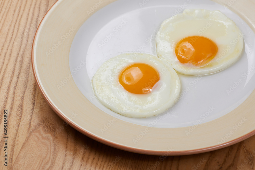 fried scrambled eggs from three eggs on a wooden table fried scrambled eggs from three eggs on a wooden table