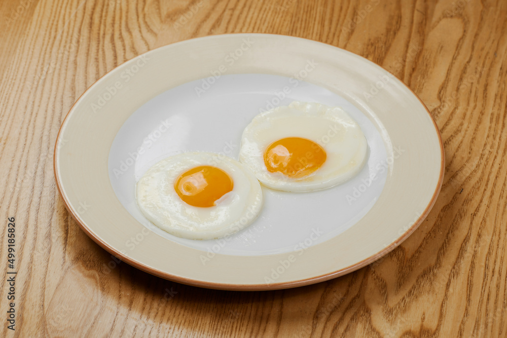 fried scrambled eggs from three eggs on a wooden table fried scrambled eggs from three eggs on a wooden table