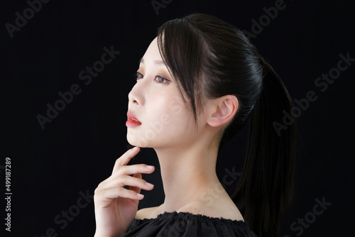 A young woman with a hand on her face and a black background