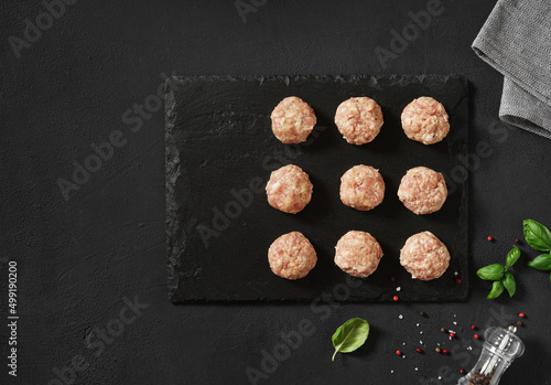 Raw meatballs with basil. Black background. Top view