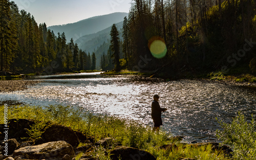 Man wading and fly fishing at dusk on the Selway & Lochsa River in the Idaho Selway Bitterroot wilderness. photo