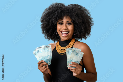 woman holding money, brazilian money, on blue background