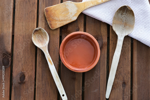 wooden spoons and earthenware pot on wooden table