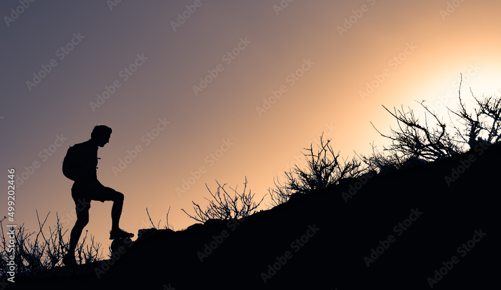 Hiker silhouette starting his climb up the mountain. Outdoor adventure, motivation and active sport concept. Hiker silhouette starting his climb up the mountain. Outdoor adventure, motivation and active sport concept.