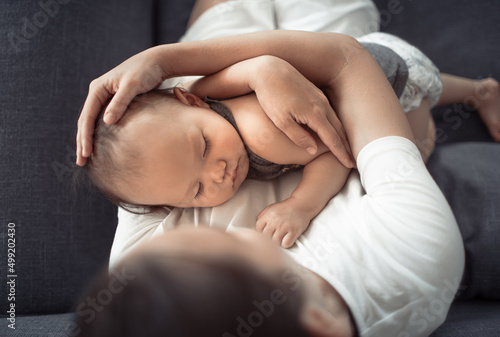Mother holding her baby sitting on sofa 