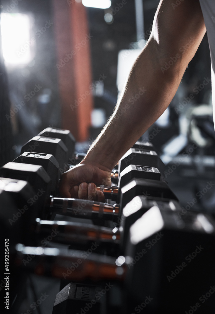 Lets grab a heavier weight. Cropped shot of an unrecognizable male athlete grabbing a set of dumbbells during his workout in the gym.