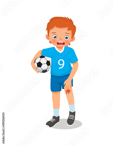 cute little boy has a knee injury crying holding his scratch bleeding leg with bruises after an accident fell down when playing soccer