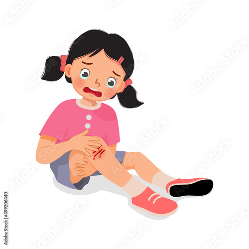 sad little girl has a knee injury crying holding her scratch bleeding leg with bruises after fell down