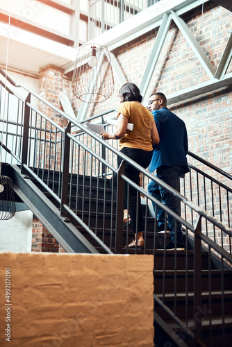 Taking the stairway to success. Shot of two designers having a discussion on a staircase in an office.