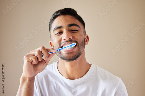 Getting my smile ready. Studio shot of a handsome young man brushing his teeth against a studio background.