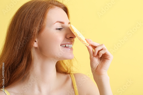 Young woman with makeup sponge on color background photo