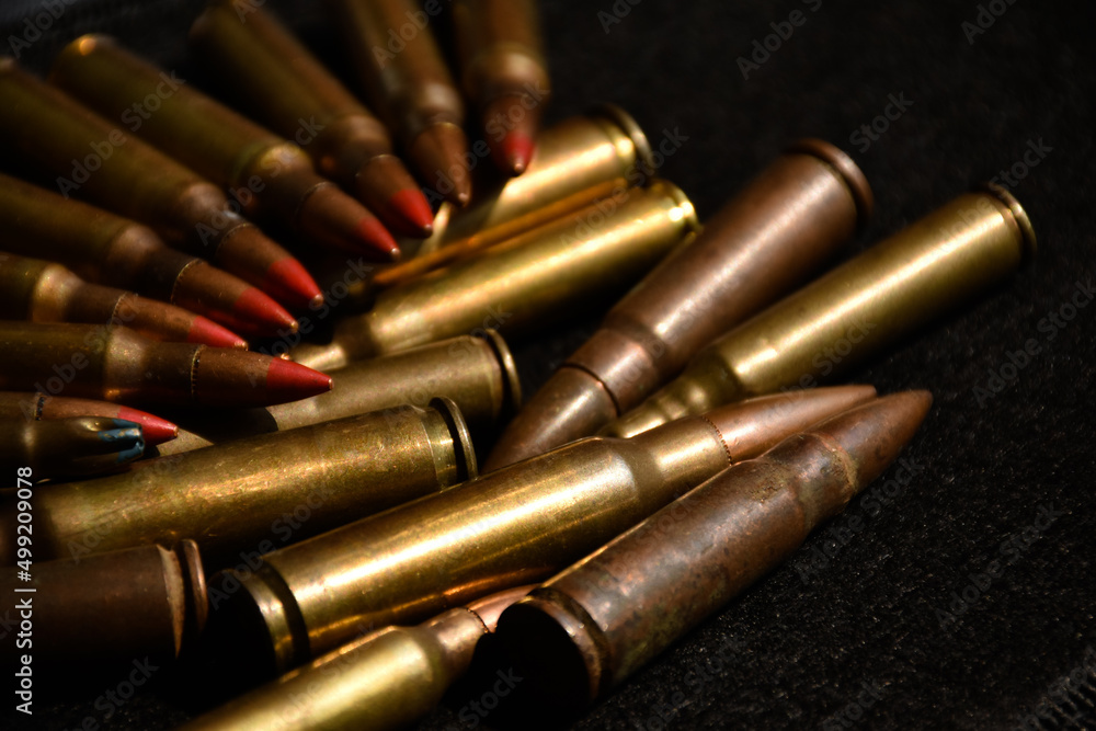 Pile M16 assault rifle cartridges on dark background.