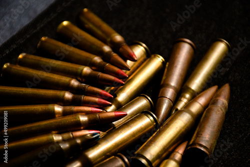 Pile M16 assault rifle cartridges on dark background.