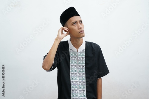 Asian muslim man doing thinking gestire, looking for idea over white background photo