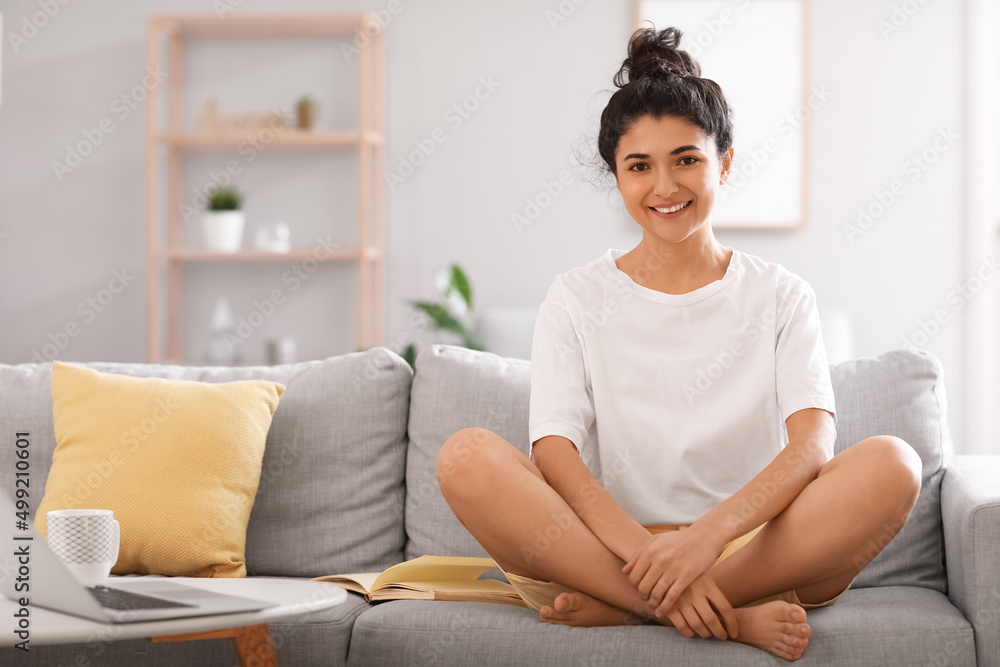 Young barefoot woman sitting on sofa at home Young barefoot woman sitting on sofa at home