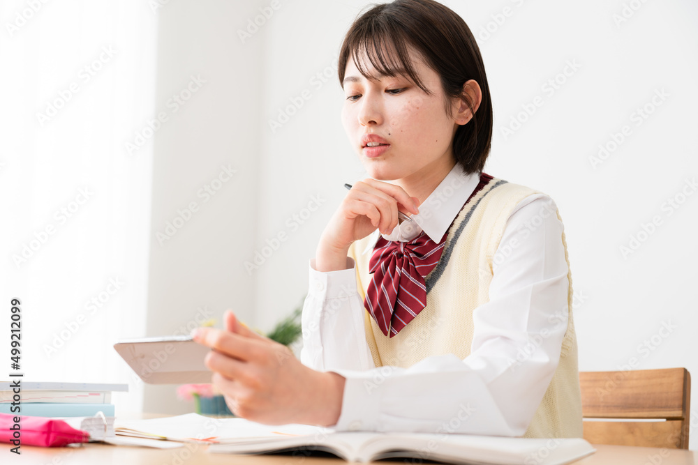 スマートフォンを観ながら勉強をする女子高生 スマートフォンを観ながら勉強をする女子高生
