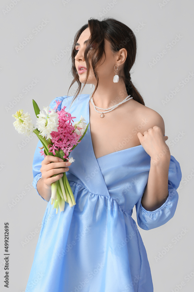 Pretty young woman with hyacinth flowers on grey background Pretty young woman with hyacinth flowers on grey background