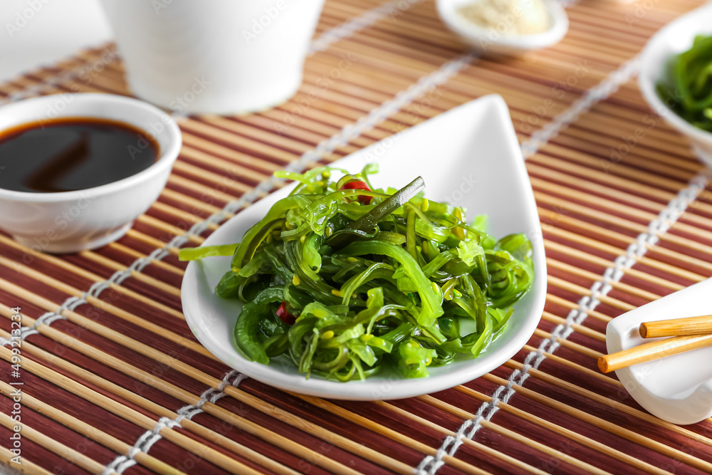 Bowls with healthy seaweed salad, sauce and sesame on light background, closeup Bowls with healthy seaweed salad, sauce and sesame on light background, closeup
