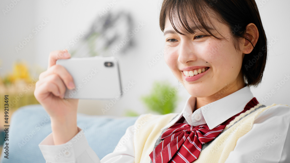 ソファーでスマートフォンを操作する女子高生