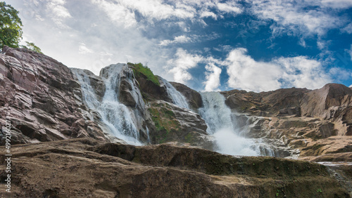 Waterfalls with blue sky, sunshine and clouds in a wide frame