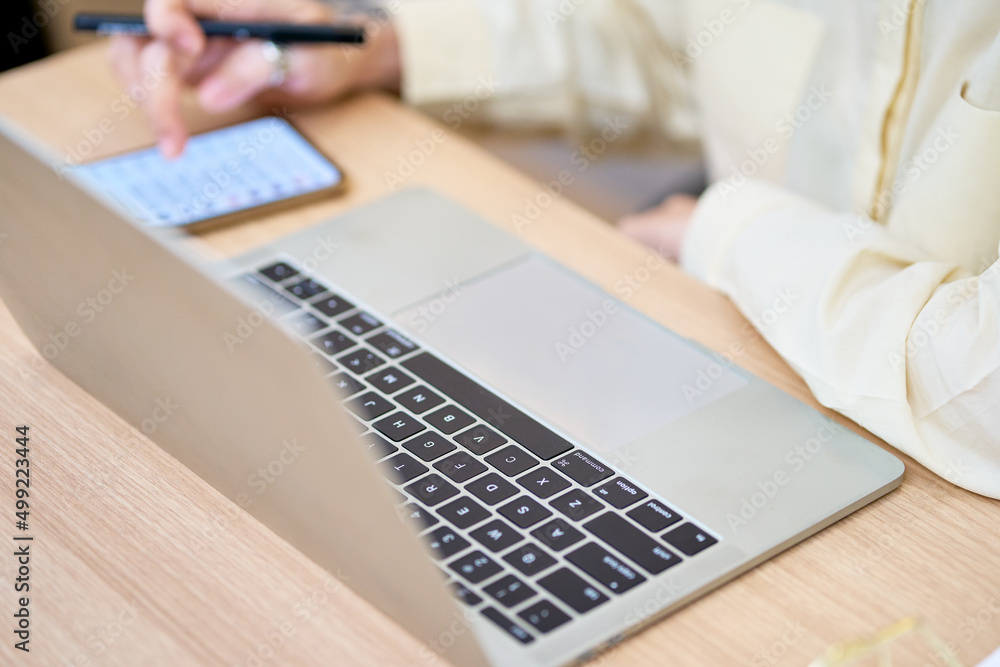 Businesswoman working with laptop and mobile phone for check order on e-commerce online Businesswoman working with laptop and mobile phone for check order on e-commerce online