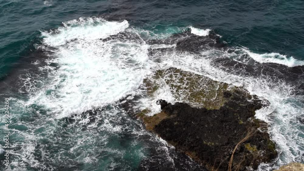 Slow motion static of ocean waves swirling and crashing and covering rocks