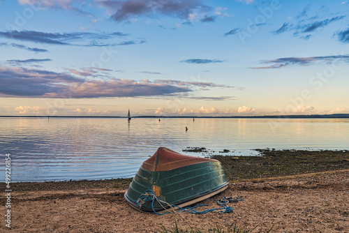 Fototapeta Naklejka Na Ścianę i Meble -  A boat on the beach, with the coast at the Jasmunder Bodden in Ralswieck, Mecklenburg-Western Pomerania, Germany