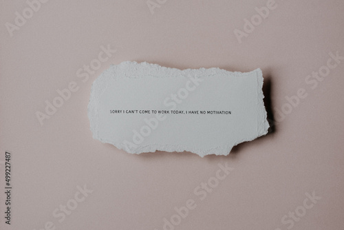 A quote about lacking motivation on a piece of scrap paper against a neutral background