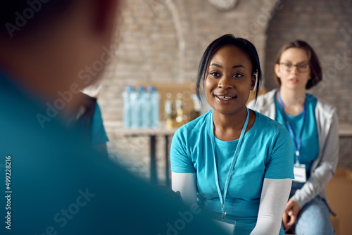 Black female volunteer having meeting with group of coworkers at humanitarian aid center. photo