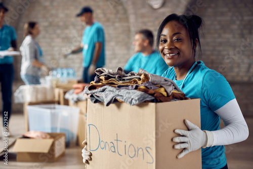 Happy African American woman volunteering at humanitarian aid center and looking at camera.