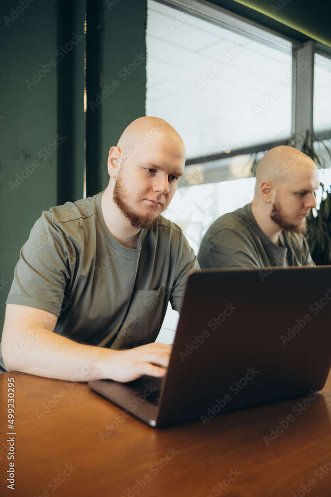 Fototapeta premium Unshaven happy man using laptop while sitting in cafe