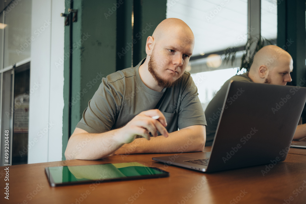 Unshaven happy man using laptop while sitting in cafe Unshaven happy man using laptop while sitting in cafe